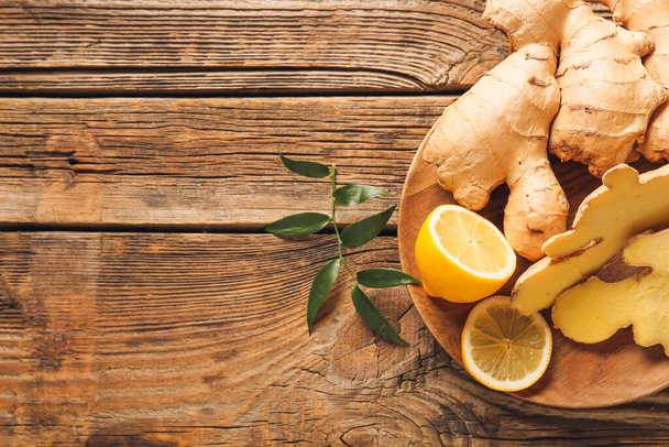 Composition with fresh ginger and lemon on wooden background - Foto, imagen