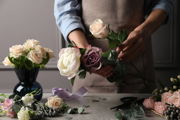 Florist creating beautiful bouquet at light grey table indoors, closeup - Fotó, kép