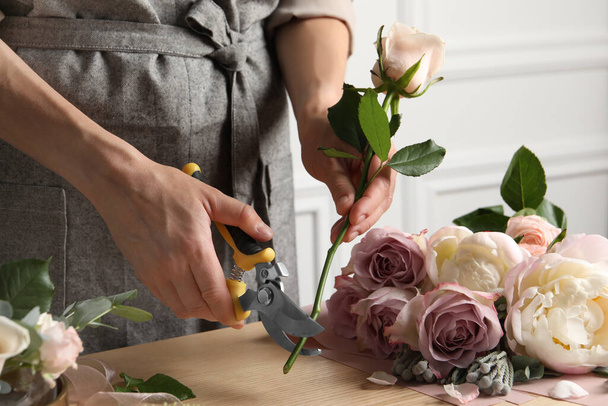 Florist cutting flower stem with pruner at workplace, closeup - 写真・画像