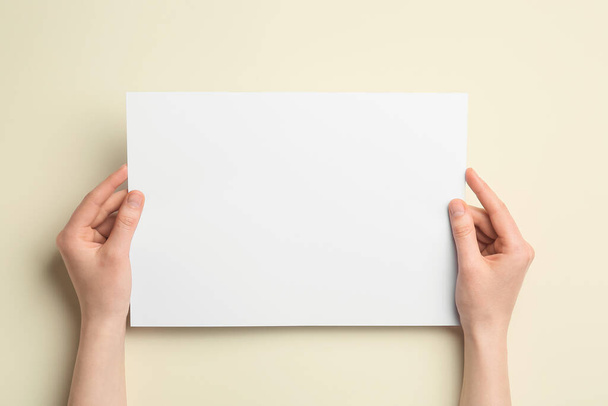 Woman holding blank sheet of paper on color background, closeup - Φωτογραφία, εικόνα