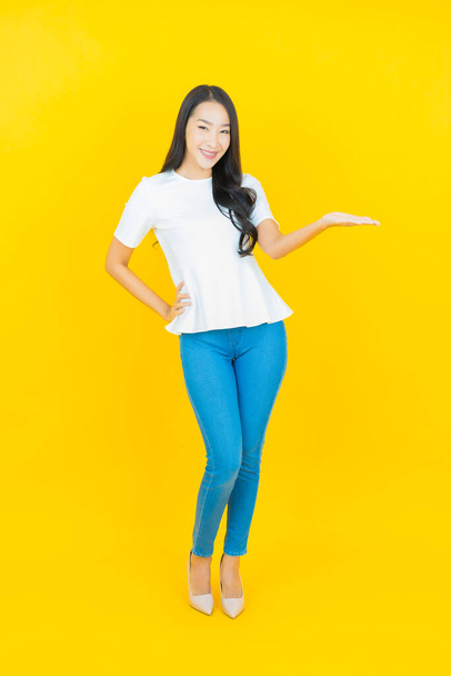 Портрет красивая молодая азиатская женщина улыбка с действием на желтый цвет фона - Фото, изображение