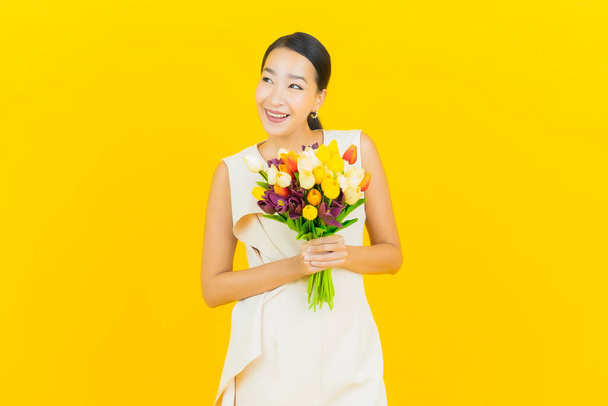 Portrait beautiful young asian woman smile with flower on yellow color background - Фото, зображення