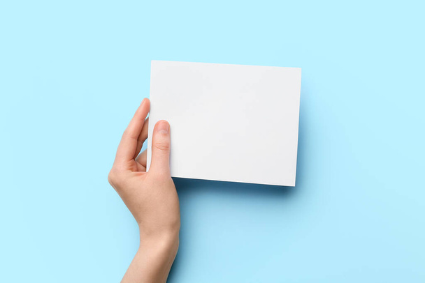 Woman holding blank sheet of paper on color background, closeup - Foto, afbeelding