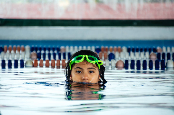Primo piano ritratto di carina bambina peruviana che nuota in piscina, bambino felice che si diverte in acqua. - Foto, immagini