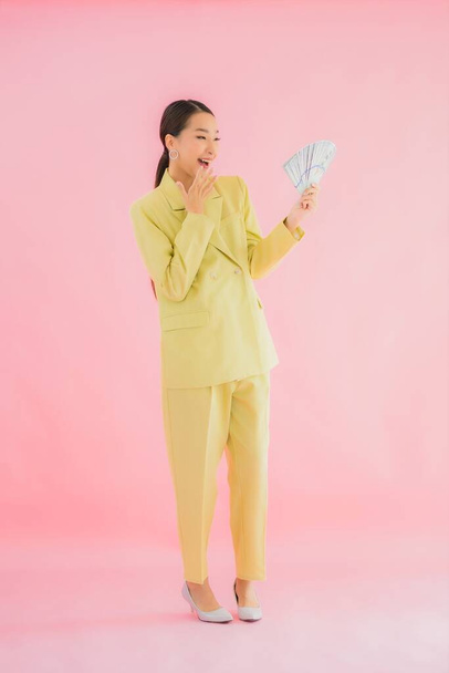 Retrato hermosa joven asiático mujer de negocios con un montón de dinero en efectivo o dinero en color de fondo - Foto, imagen