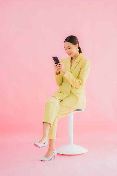 Портрет красива молода азіатська бізнес-леді використовує смартфон з чашкою кави на кольоровому фоні
 - Фото, зображення