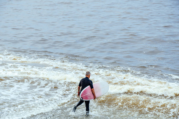 Surfista. Surfista con tavola da surf che cammina in mare. Stile di vita sano, attività acquatiche, sport acquatici. - Foto, immagini