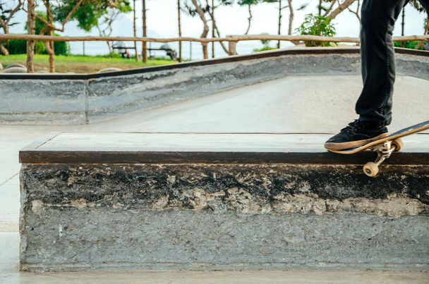 Skateboarder κάνει ένα στραβό κόλπο τρόχισμα σε ένα παγκάκι στο skatepark. - Φωτογραφία, εικόνα