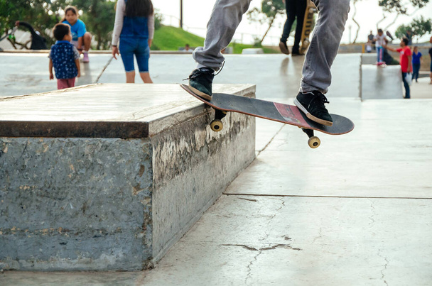 Skateboarder está fazendo um truque de moagem torto em um banco no skatepark. - Foto, Imagem