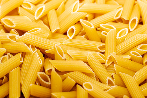 Italiaanse penne pasta gecanneleerd close-up achtergrond achtergrond. Hoge kwaliteit foto - Foto, afbeelding