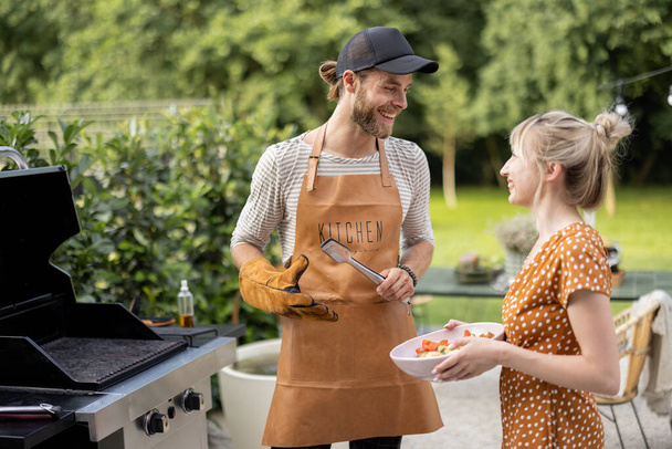Couple grilling food at backyard - Foto, afbeelding
