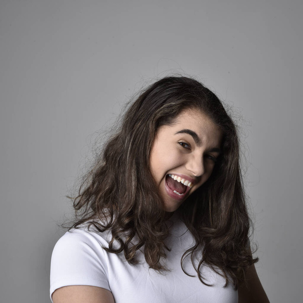 Close up retrato de jovem mulher com cabelo castanho natural, sobre as expressões faciais superiores em fundo estúdio cinza claro. - Foto, Imagem