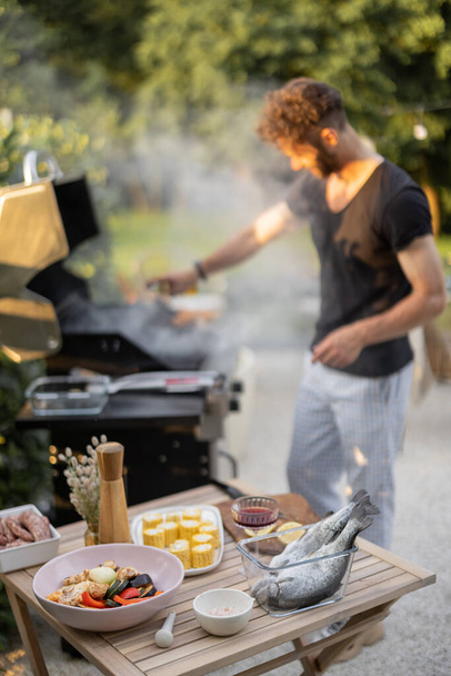 Man cooking fish and vegetables on a grill outdoors - Fotoğraf, Görsel