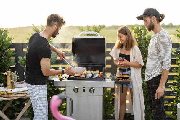 Young friends grilling at backyard - Foto, imagen