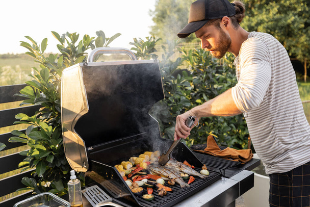 Man cooking on a grill outdoors - Photo, Image