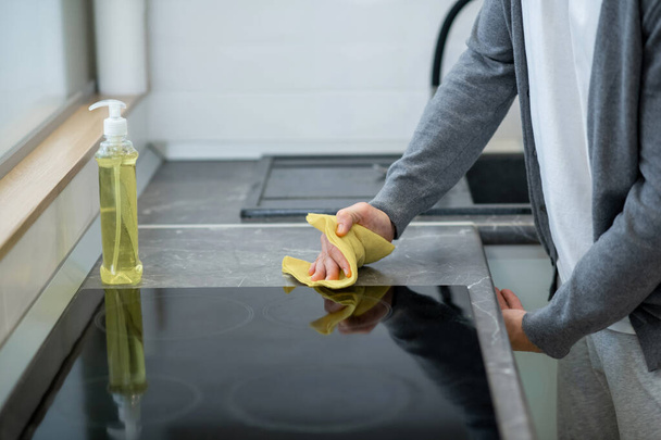 Close up picture of a man cleaning the surface of the table in the kitchen - Foto, afbeelding