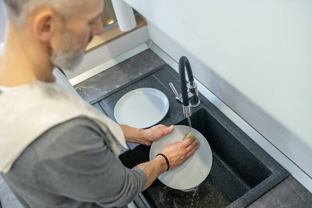 Close up of a man washing the plates in the kitchen - Foto, Imagen