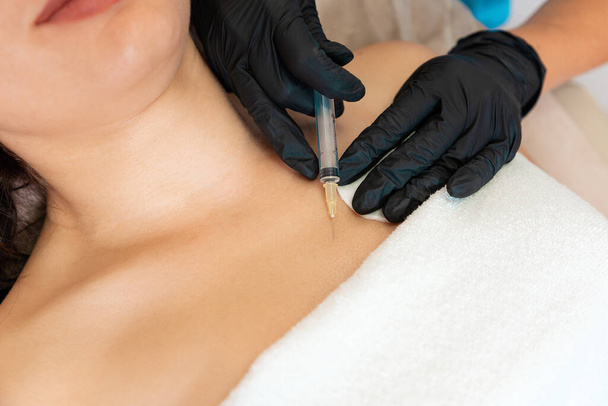 Профессиональный косметолог делает инъекцию гиалуроновой кислоты у груди клиента. Закрывай. Концепция пластической хирургии и подъема. - Фото, изображение