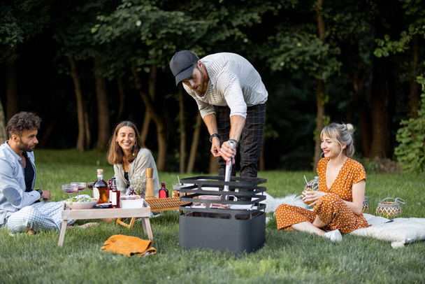 Vrienden samen op de picknick met barbecue en wijn - Foto, afbeelding