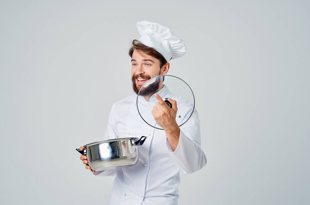 chef masculin avec une casquette sur la tête une casserole dans ses mains cuisine cuisine - Photo, image