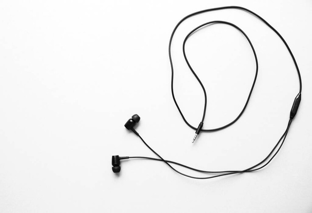 Écouteurs couchés sur le fond rose. Concept de musique moderne. Technologie audio. - Photo, image