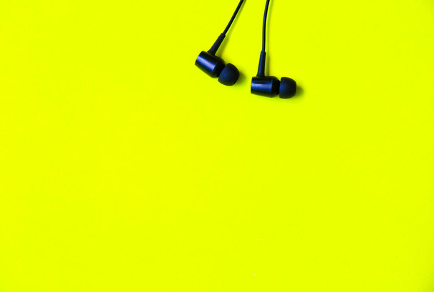 Earphones lying on the green background. Modern music concept. Audio technology. - Photo, Image