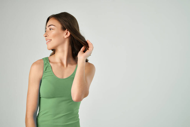 pretty brunette holding hair fashion hairstyle green tank top isolated background - Photo, Image
