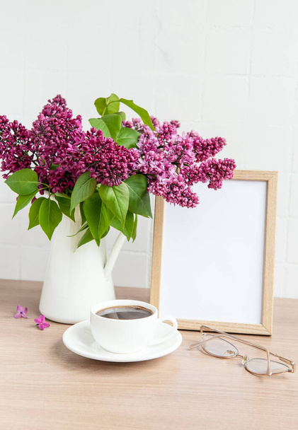 Kytice fialových květin ve váze a prázdném rámu na dřevěném stole. - Fotografie, Obrázek