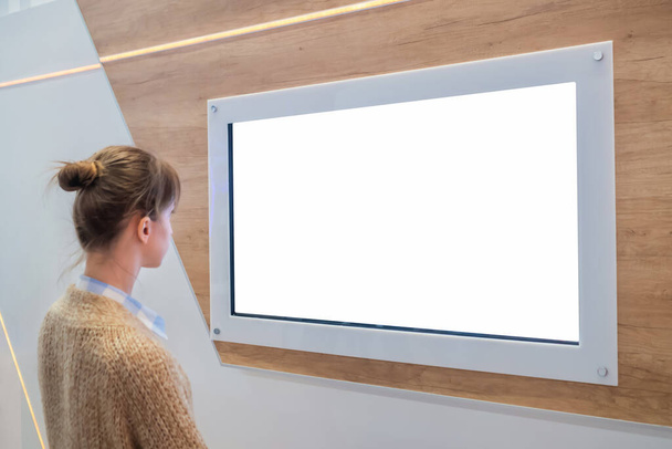 Mujer mirando la pared de exhibición blanca en blanco en exposición - concepto de pantalla blanca - Foto, Imagen