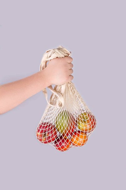 Mão segurando legumes de frutas em saco de algodão de malha reutilizável, conceito de resíduos zero livre de plástico. - Foto, Imagem