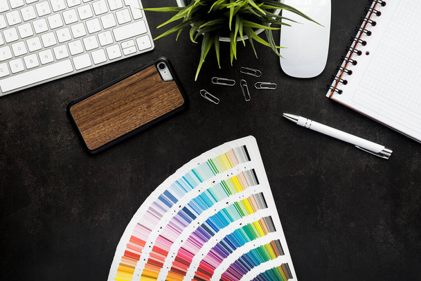 Siyah masa ve klavyeli grafik tasarımcı çalışma alanı, bitki, fare, not defteri, akıllı telefon ve kalem - üst görünüm - Fotoğraf, Görsel