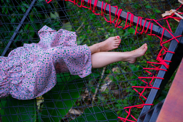 美しいアジアの女性の足が自然の中で休息とリラックスするためにネットバルコニーに横たわっ. - 写真・画像