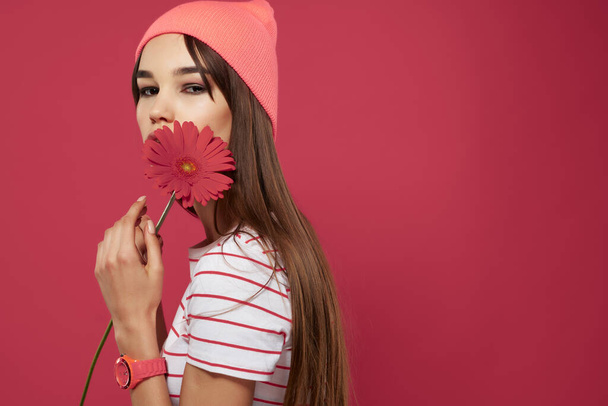 ブルネットはピンクの帽子の赤い花の化粧装飾を身に着けている - 写真・画像