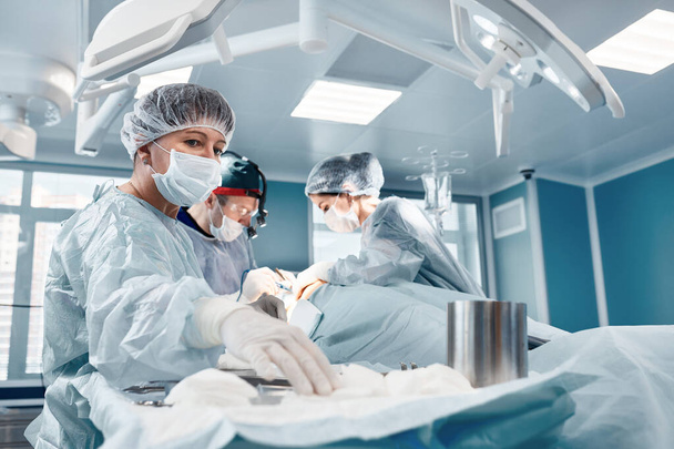 外科医のチームのハードワーク、複雑で長時間の手術中の専門医のハードワーク、外科病棟の劇場、命を救う. - 写真・画像