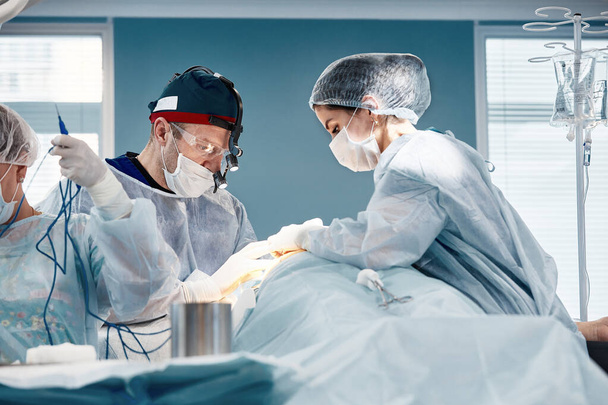 The surgical team operates on the patient in the operating room. A well-trained anesthesiologist with sophisticated apparatus accompanies the patient throughout the entire operation. - Φωτογραφία, εικόνα