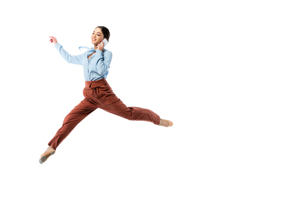 Smiling ballerina talking on smartphone while jumping isolated on white  - Foto, Imagem