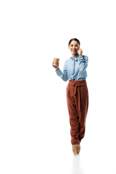 Smiling ballerina holding coffee to go and talking on smartphone on white background  - Foto, Imagem