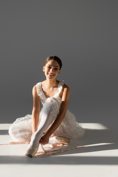 Young ballerina wearing pointe shoes on grey background  - Zdjęcie, obraz