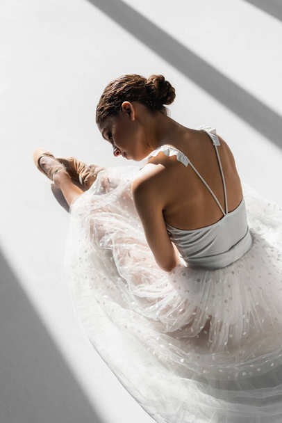 Vista ad alto angolo della ballerina appoggiata su sfondo bianco con luce solare - Foto, immagini