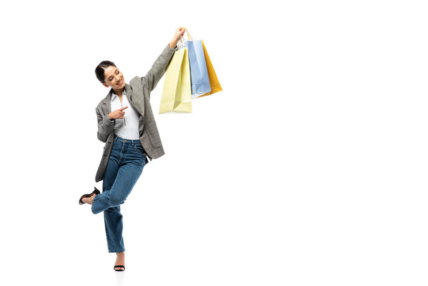 Smiling woman pointing with finger at shopping bag on white background  - Foto, Bild