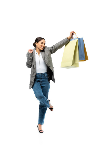 Boldog nő mutat igen gesztus, miközben a gazdaság bevásárló táskák fehér háttér  - Fotó, kép