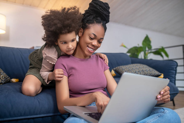 African american woman and little girl looking into laptop - Foto, immagini
