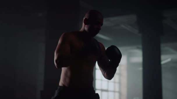 Boxeador masculino pateando saco de boxeo. Hombre practicando patadas en bolsa de deporte - Imágenes, Vídeo