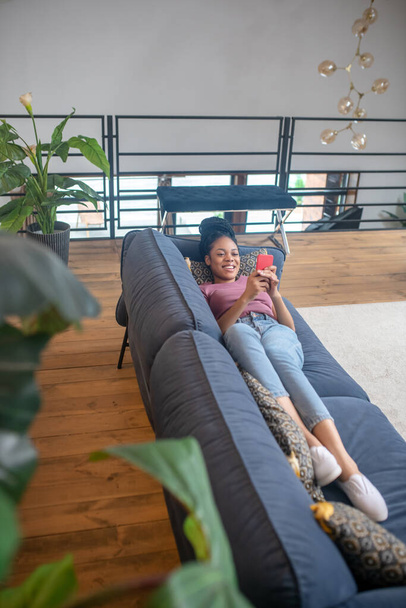 Cute african american woman lying on sofa at home - Foto, imagen