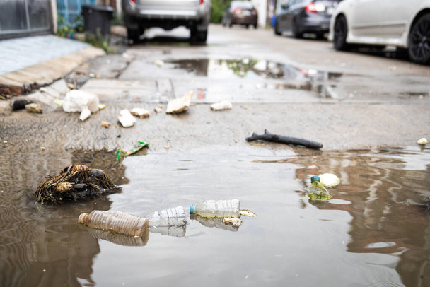 Müll und Schmutzwasser, nach Starkregen und Überschwemmungen überall auf der Straße verstreuter Müll, Schmutz aus Schutt, Abfallstücken, in der Flut treibenden Plastikflaschen, Umweltverschmutzung - Foto, Bild