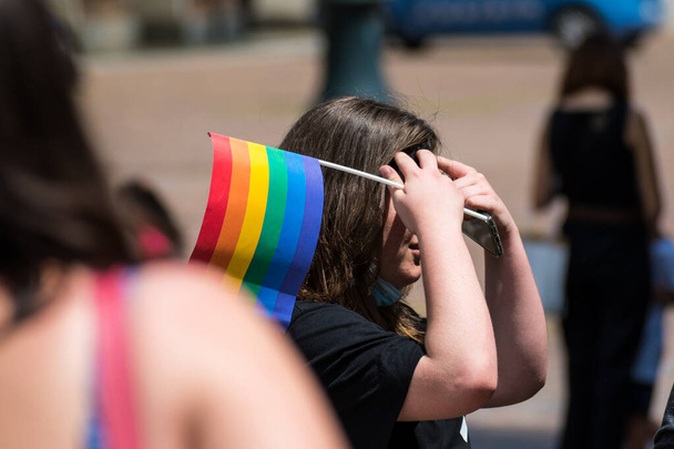 Gruppo di giovani alla sfilata dell'orgoglio sulla strada della città con bandiera dell'arcobaleno gay, a sostegno dei diritti e della diversità gay  - Foto, immagini