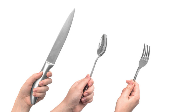 Ensemble de couverts de cuisine. Main de femme avec couteau, fourchette et cuillère en acier, isolée sur fond blanc - Photo, image