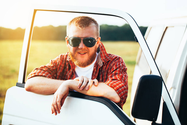 Blond driver in sunglasses stands near his car - 写真・画像