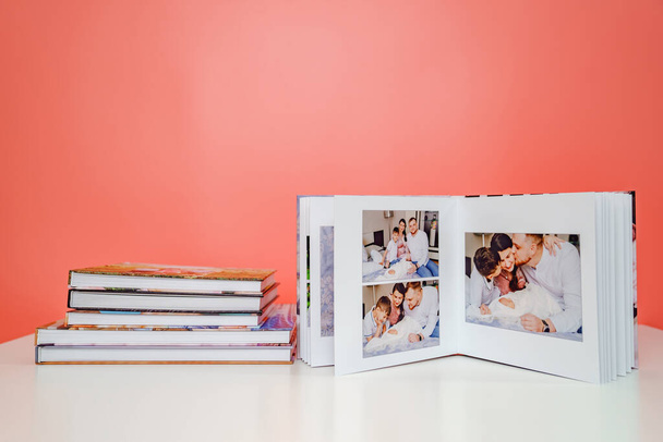 on pink background photobooks. open album from family photo shoot with newborn - Foto, Imagem