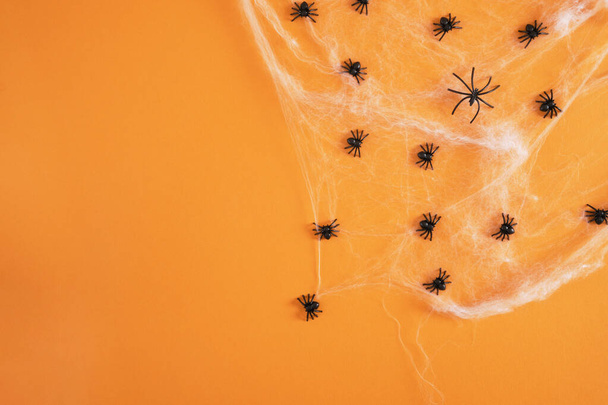 many black plastic spiders in a web on an orange background copy space halloween concept - Valokuva, kuva
